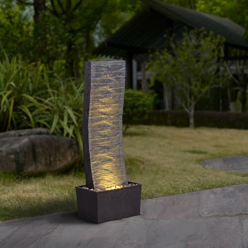 Curved water fountain with lights in a garden setting.