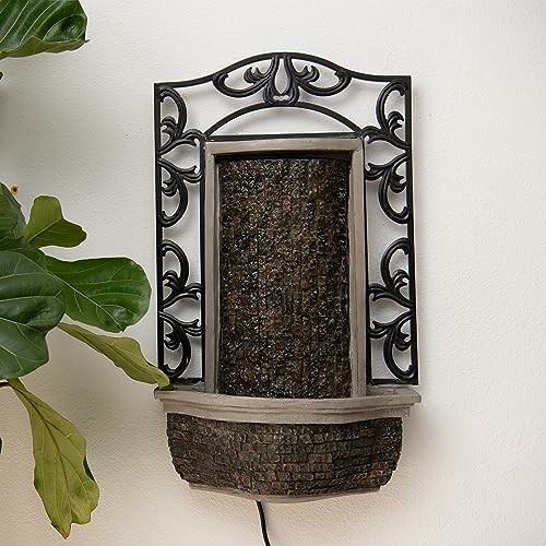 Decorative wall-mounted fountain with intricate black metal frame.