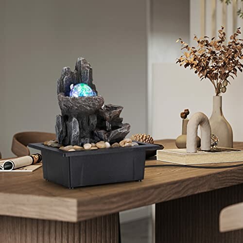 Indoor tabletop water fountain with rocks and decorative elements.